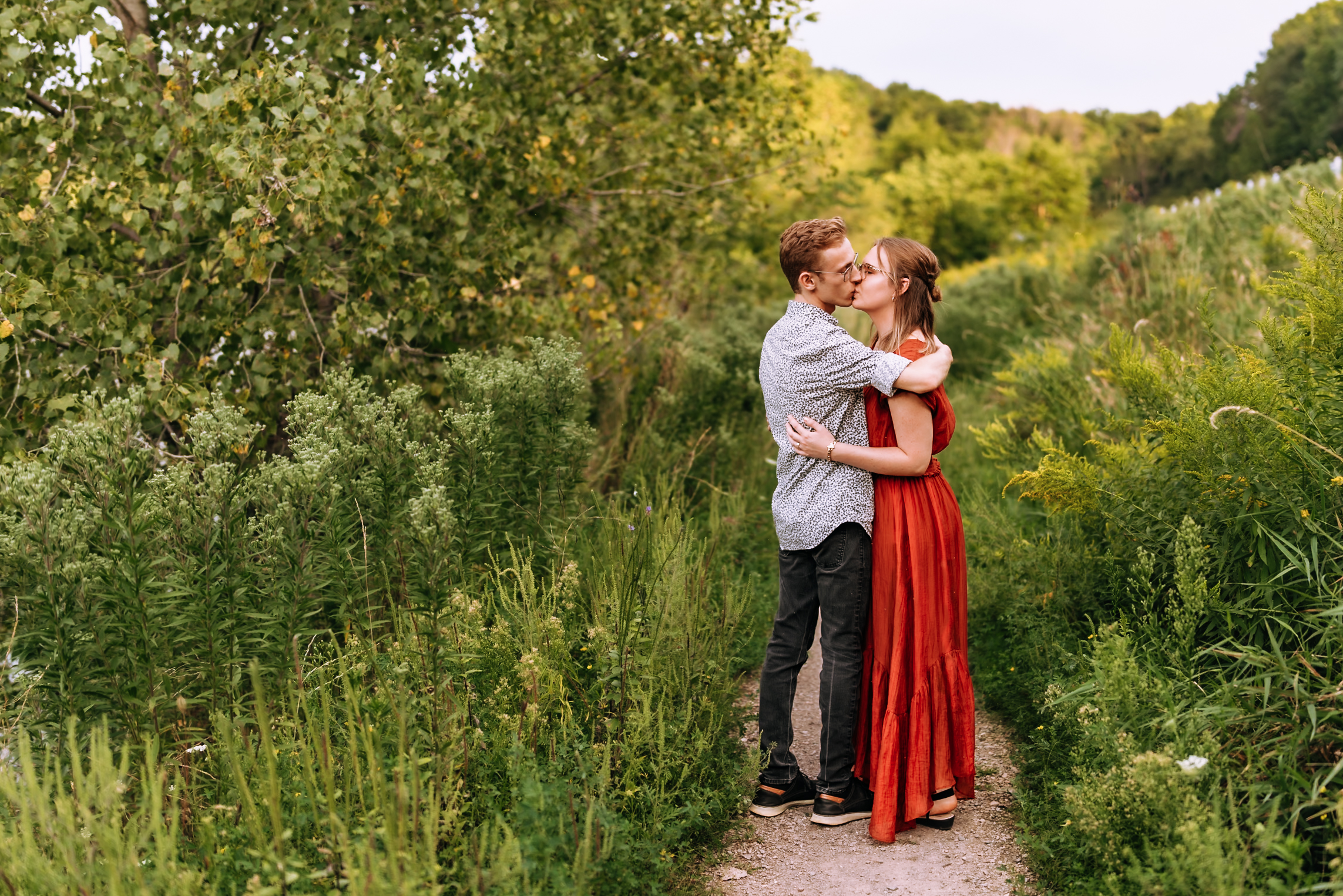Courtney & Joel Engagement Photo - Kissing in a grassy field
