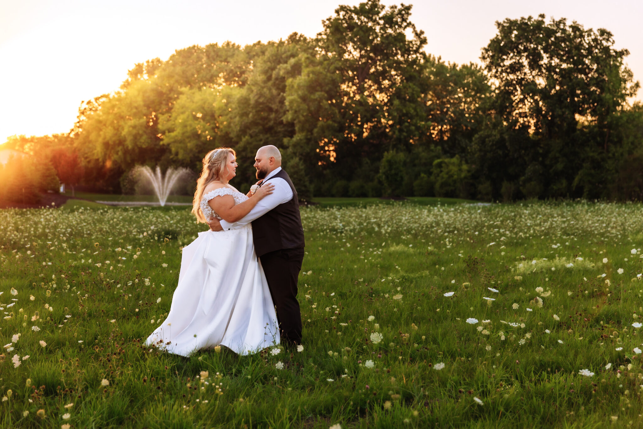 Jennifer & Lukas wedding photo, in a grassy field with the sunset behind them
