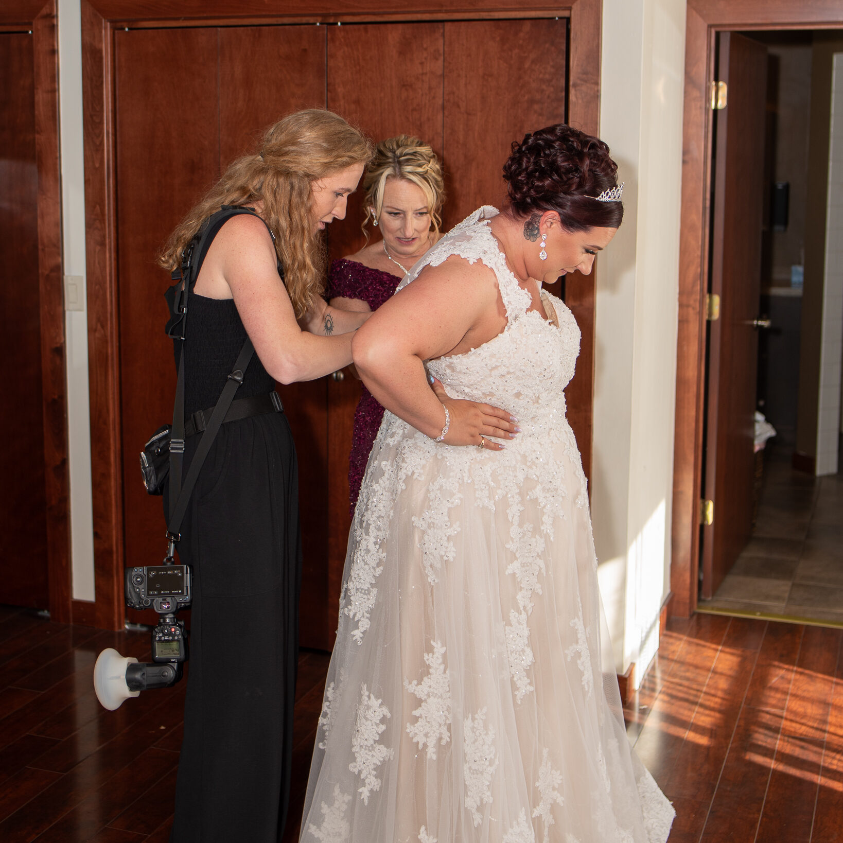 Erica, photographer, assisting bride with buttons on her dress